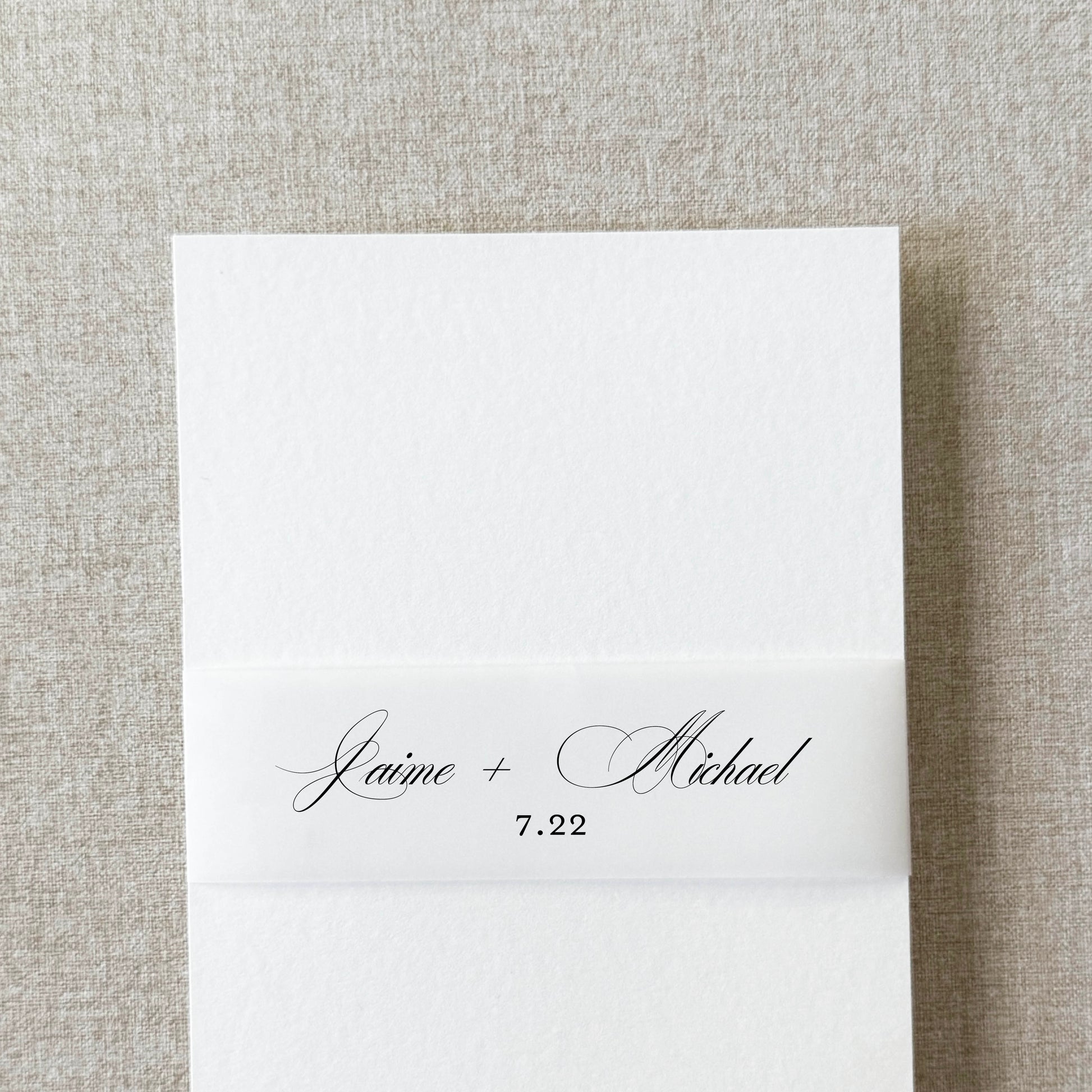 Custom monogram belly band in formal script wrapped around a wedding invitation