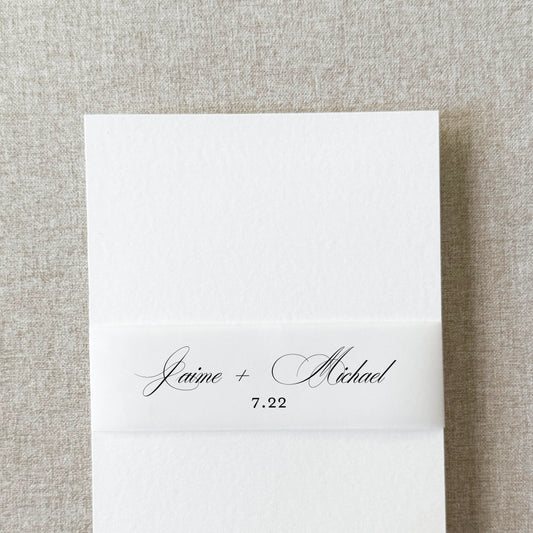 Custom monogram belly band in formal script wrapped around a wedding invitation